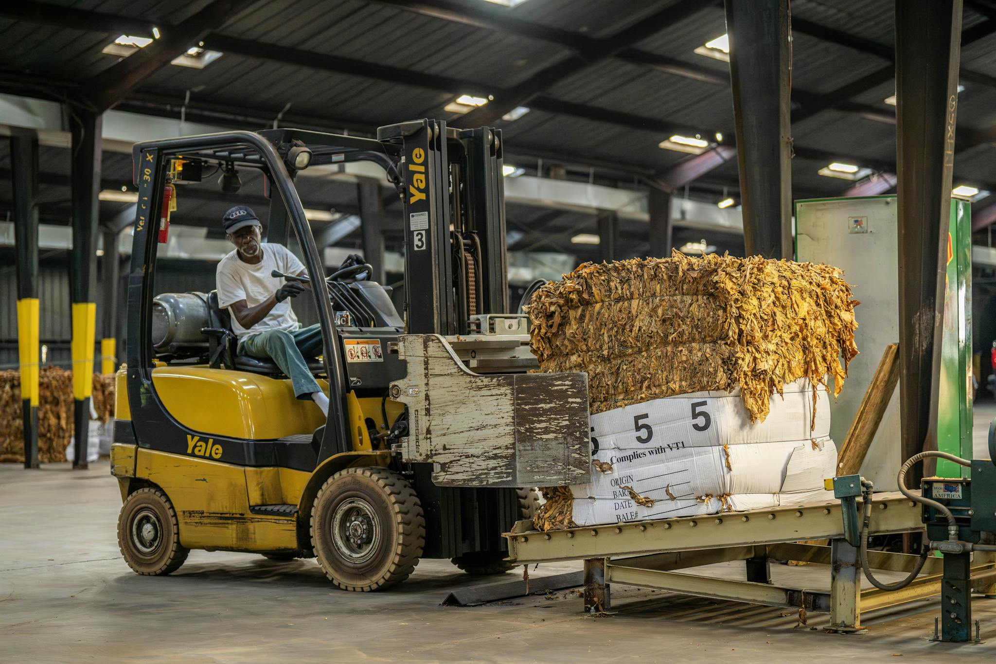 Forklift operator transporting packaged material in an industrial warehouse, showcasing logistics and industry work.