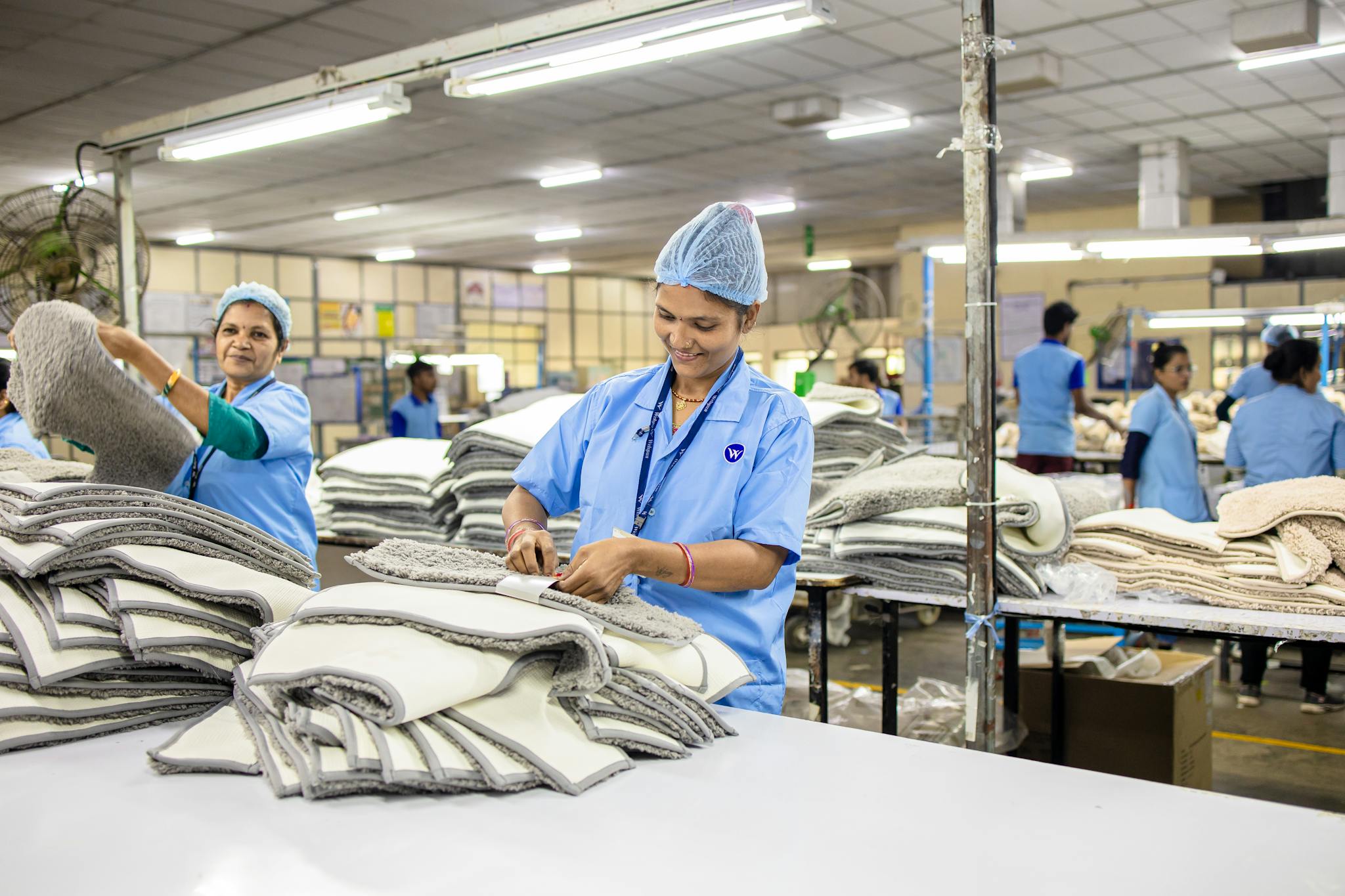 Workers in a textile factory sorting piles of fabric, highlighting teamwork and industry in garment production.